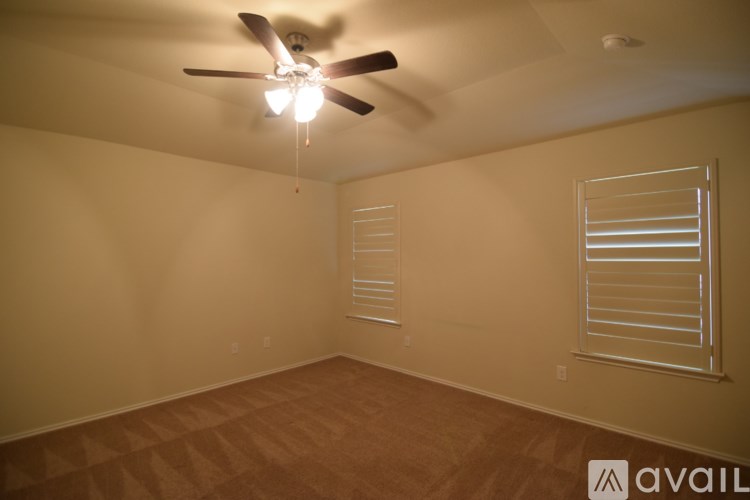 A room with a ceiling fan and a window with blinds.