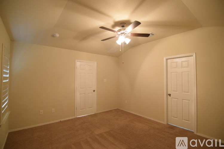 A room with a ceiling fan and two doors.