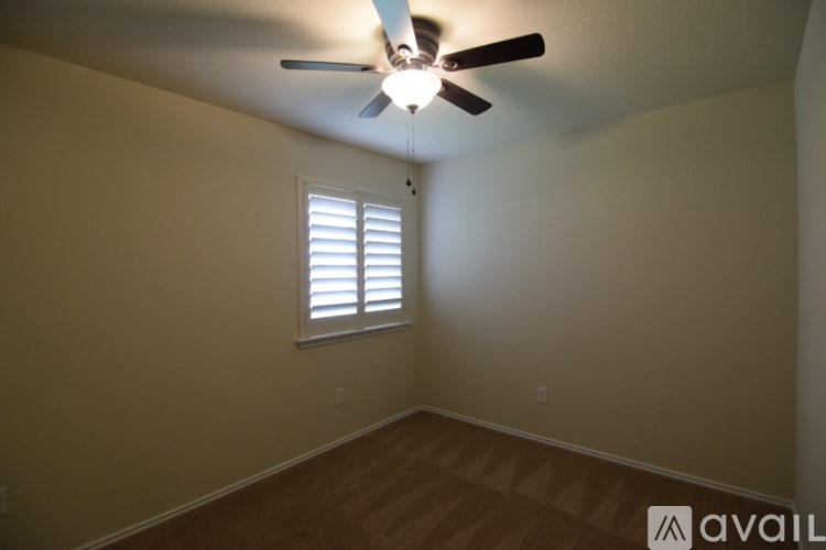 A room with a ceiling fan and a window with blinds.