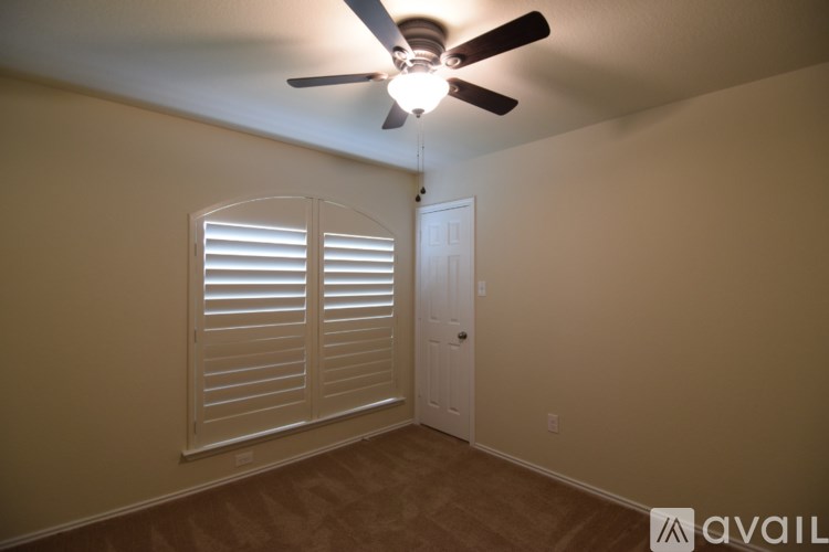 A room with a ceiling fan and a door.