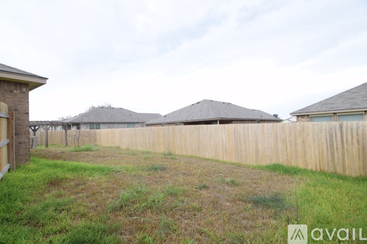 A grassy area with a wooden fence and houses in the background.