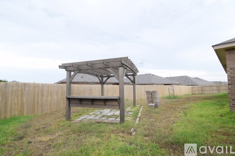 A wooden pergola stands in a grassy backyard.
