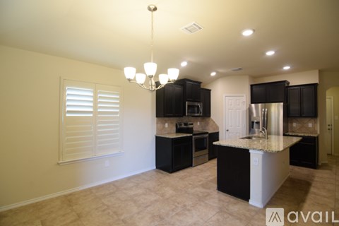 A kitchen with black cabinets and a granite countertop.