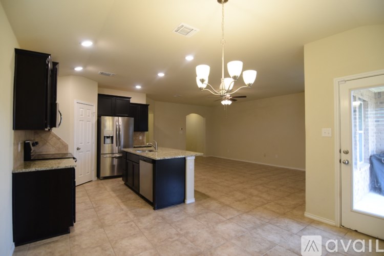 A kitchen with black cabinets and a black fridge is shown.