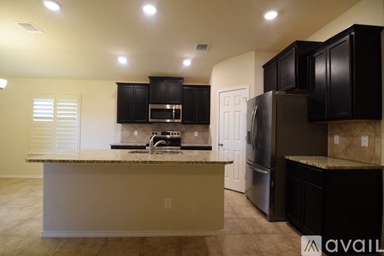 A kitchen with black cabinets and a granite countertop.