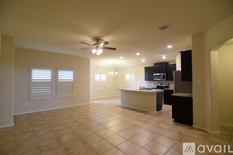 A spacious kitchen and living room with a ceiling fan and tiled flooring.