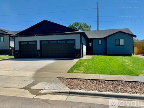 A blue house with a grey garage door is available for rent.