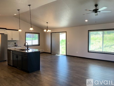 A modern kitchen with a black island and pendant lights.