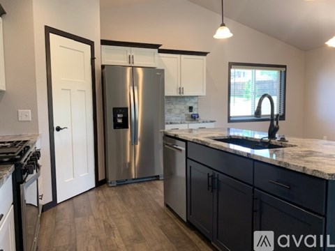 A kitchen with a stainless steel refrigerator and wooden floors.