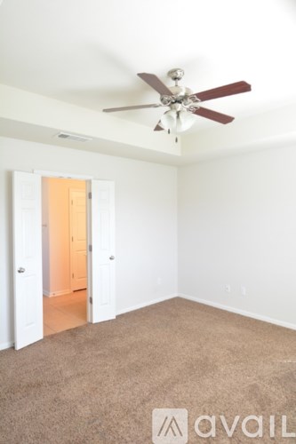 A room with a ceiling fan and carpeted floor.
