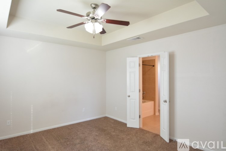 A room with a ceiling fan and a doorway leading to another room.