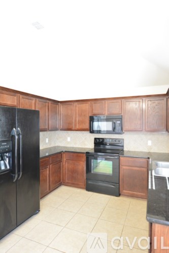 A kitchen with black appliances and wooden cabinets.