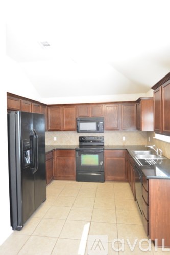 A kitchen with a black refrigerator, black oven, and black stove.