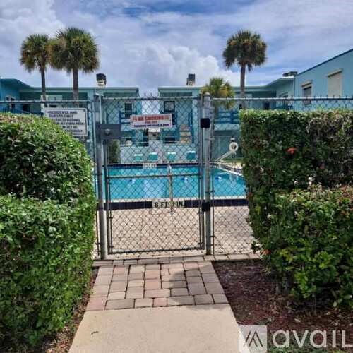 A pool is surrounded by a fence and hedges.