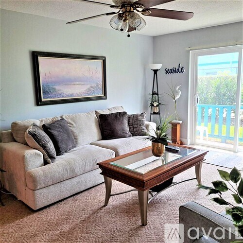 A living room with a couch, coffee table, and a painting on the wall.