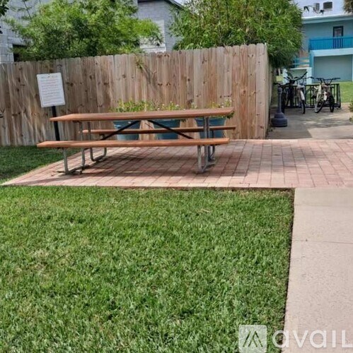 A wooden picnic table sits in a grassy area next to a wooden fence.