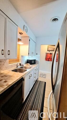 A kitchen with white cabinets and a black fridge.