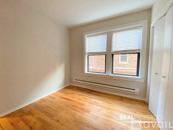 A room with wooden flooring and a window with blinds.
