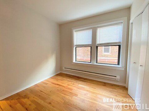 A room with wooden flooring and a window with blinds.