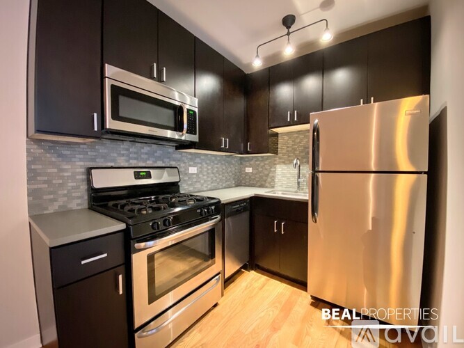 A modern kitchen with black cabinets and stainless steel appliances.