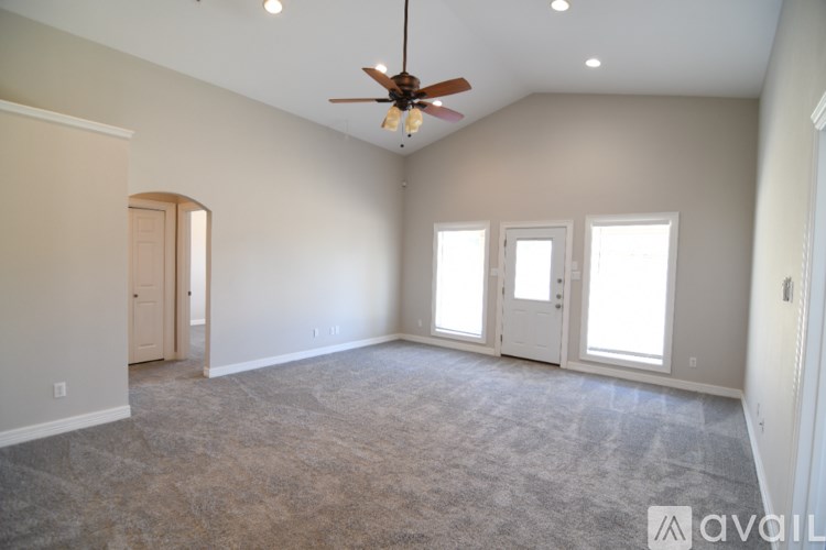A spacious room with a ceiling fan and carpeted floor.