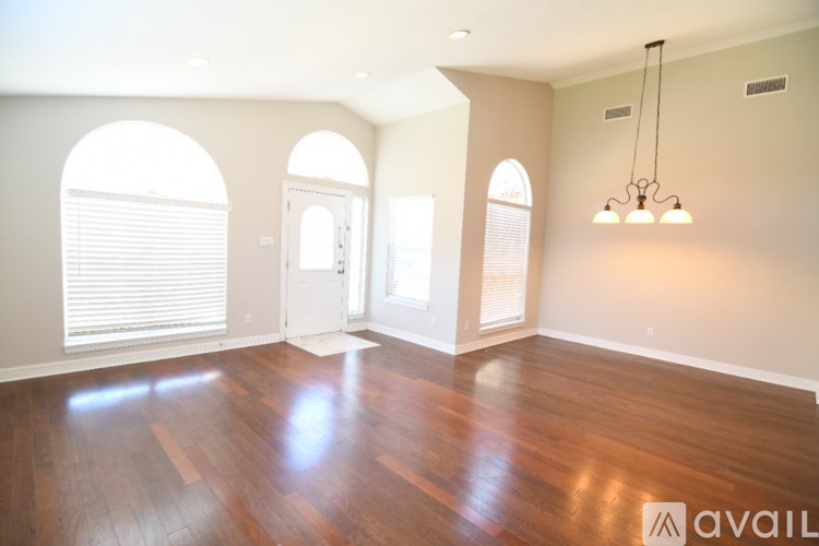 A room with wooden floors and arched windows.