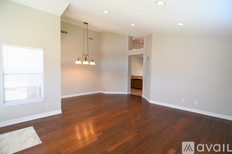 A large empty room with wooden floors and a chandelier.