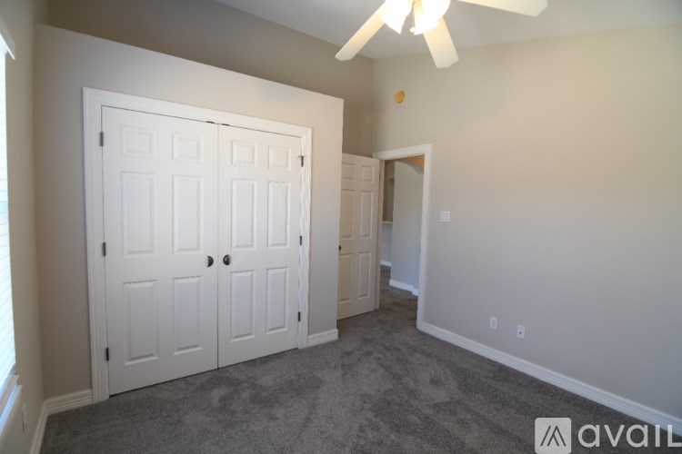 A room with a white door and a ceiling fan.