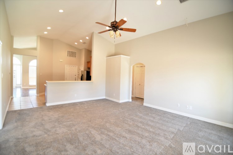 A spacious room with a ceiling fan and carpeted floor.