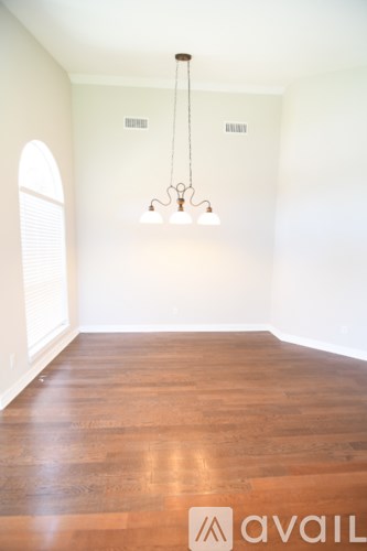 A room with wooden floors and a chandelier hanging from the ceiling.