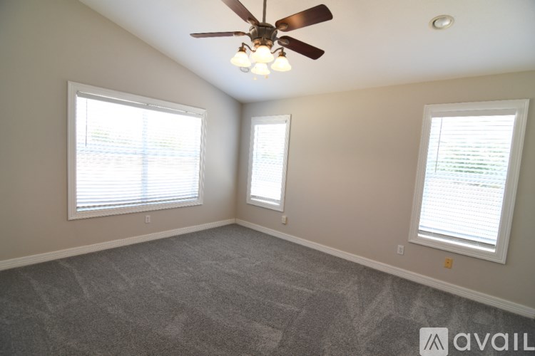 A room with a ceiling fan and two windows.