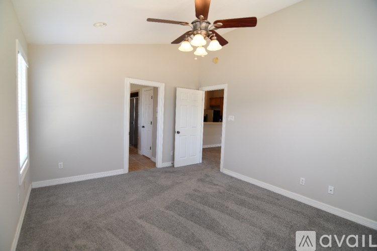 A room with a ceiling fan and carpeted floor.