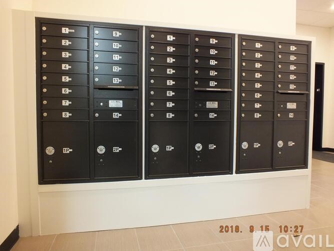 A row of black mailboxes are lined up against a wall.