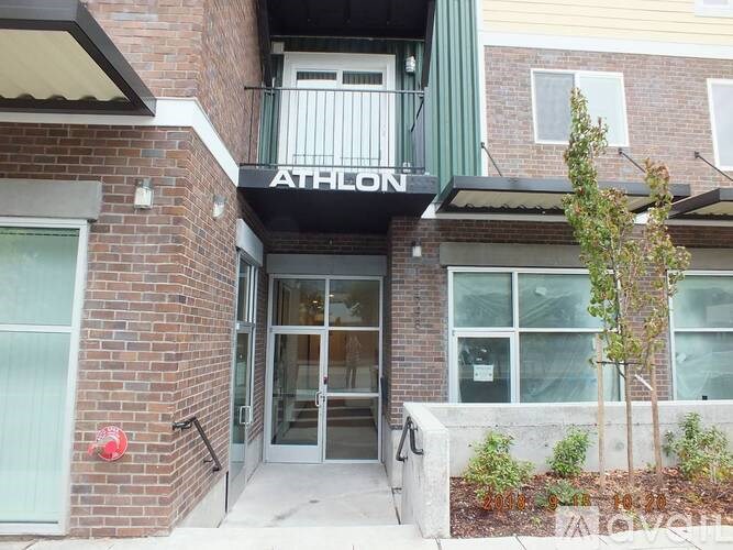The front of a brick building with a glass door and a sign that says "ATHLON".