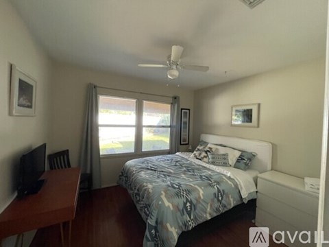 A bedroom with a bed, desk, and window.