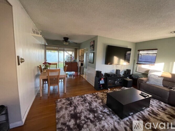 A living room with a black coffee table and a flat screen TV mounted on the wall.