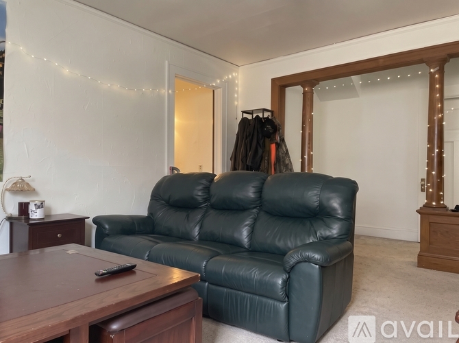 A Christmas tree stands in a living room with a couch and a coffee table.