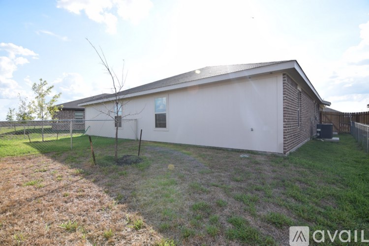 A small white building with a brown roof and a fence in front of it.