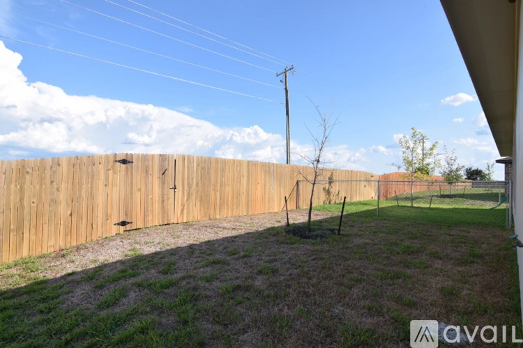 A wooden fence in a backyard with a clear blue sky.