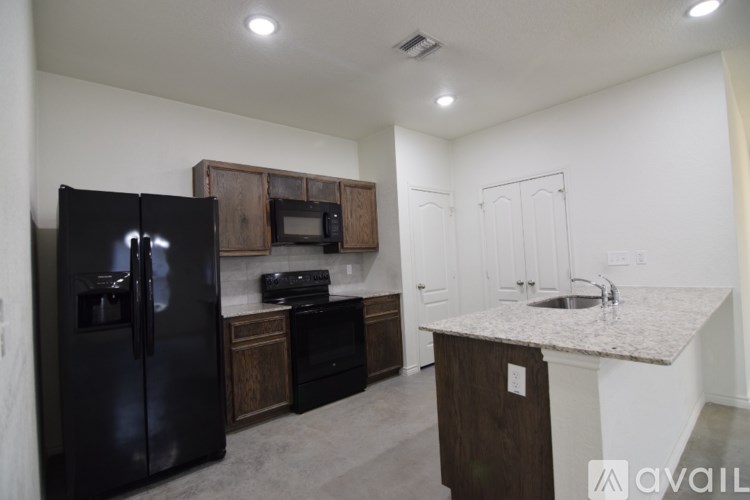 A kitchen with a black fridge, microwave, and oven.