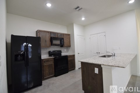 A kitchen with a black fridge, microwave, and oven.