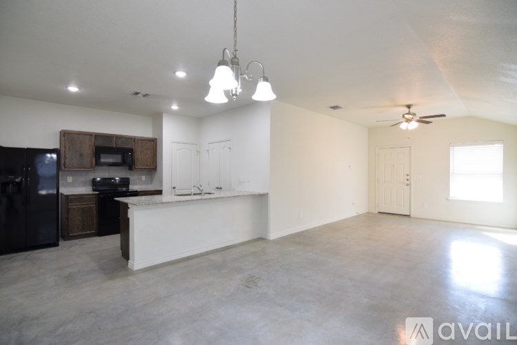 A spacious kitchen with a black fridge, microwave, and a white countertop.