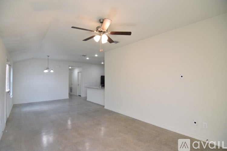 A spacious room with a ceiling fan and a door in the background.