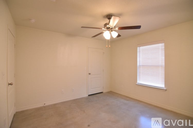 A room with a ceiling fan and a window with blinds.