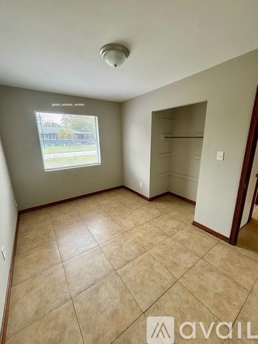 A room with beige tiled flooring and a window showing an outdoor view.