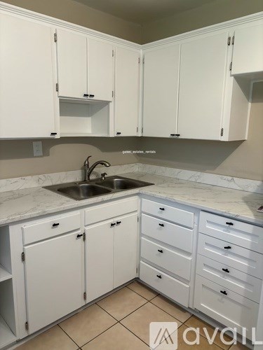 A kitchen with white cabinets and a marble countertop.