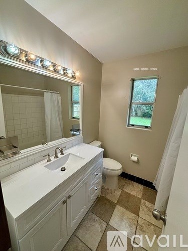 A bathroom with a sink, toilet, and a window.