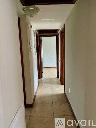A hallway with a tiled floor and a door at the end.