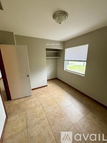 A room with beige tiled flooring and a window with blinds.