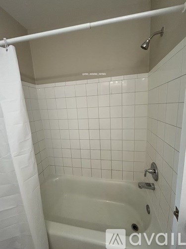 A white bathroom with a white tub and white tiles.